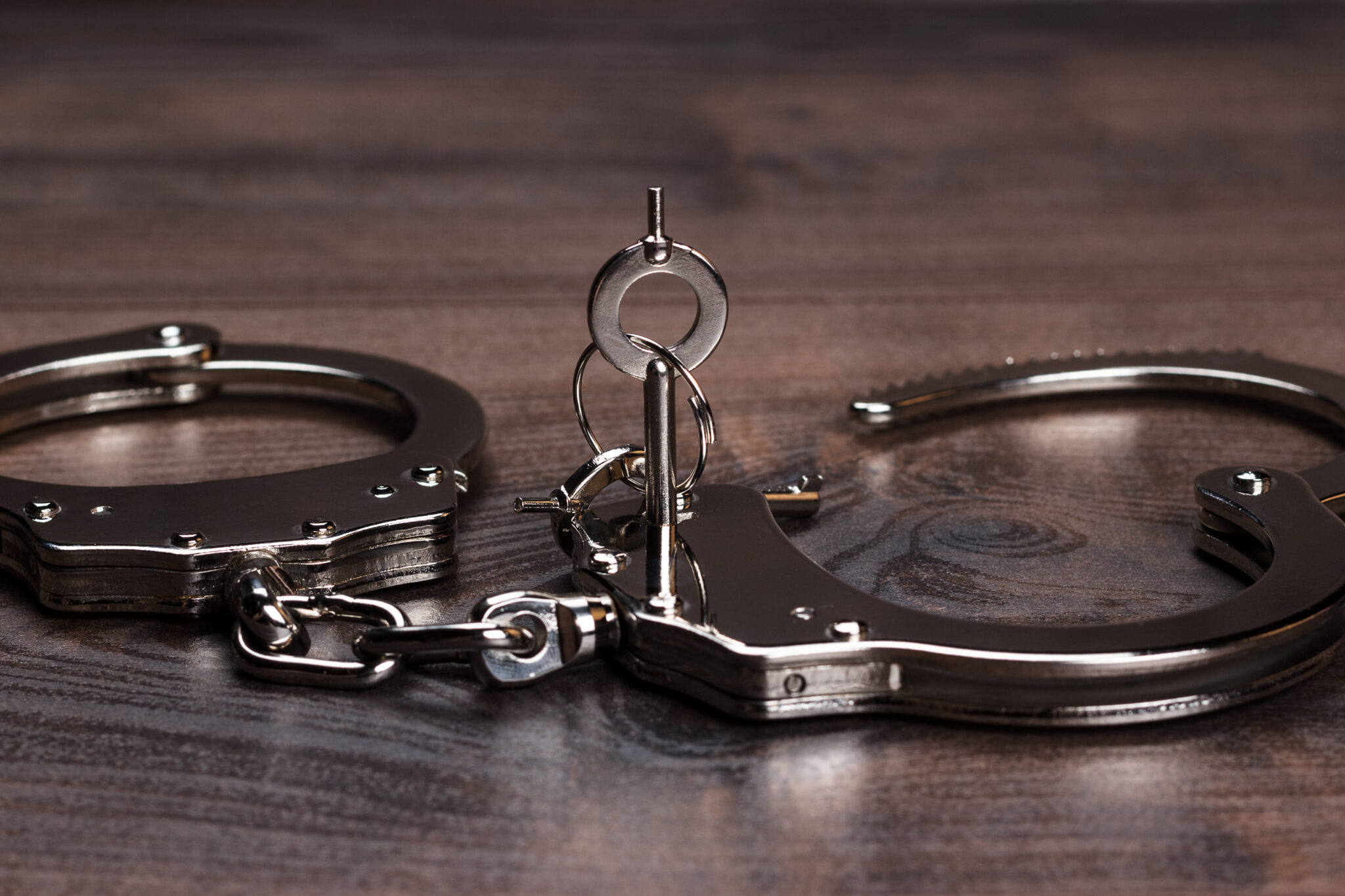 handcuffs and keys on brown wooden table background